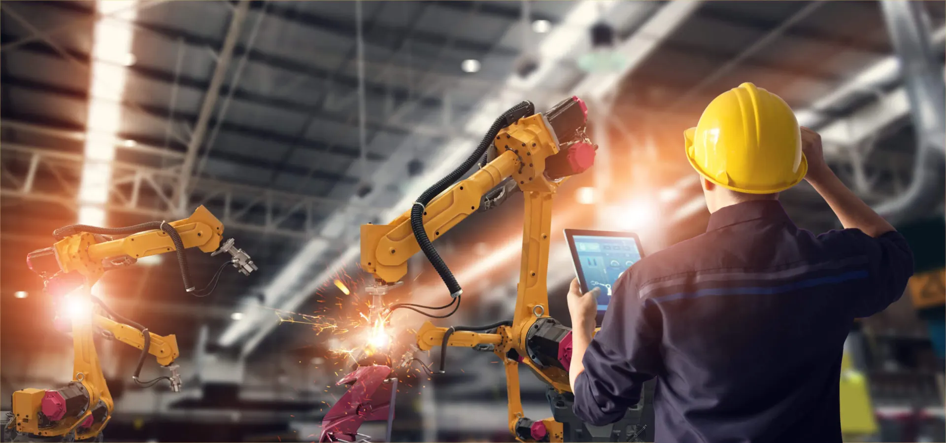 Technicien pilotant des robots de soudage depuis une tablette