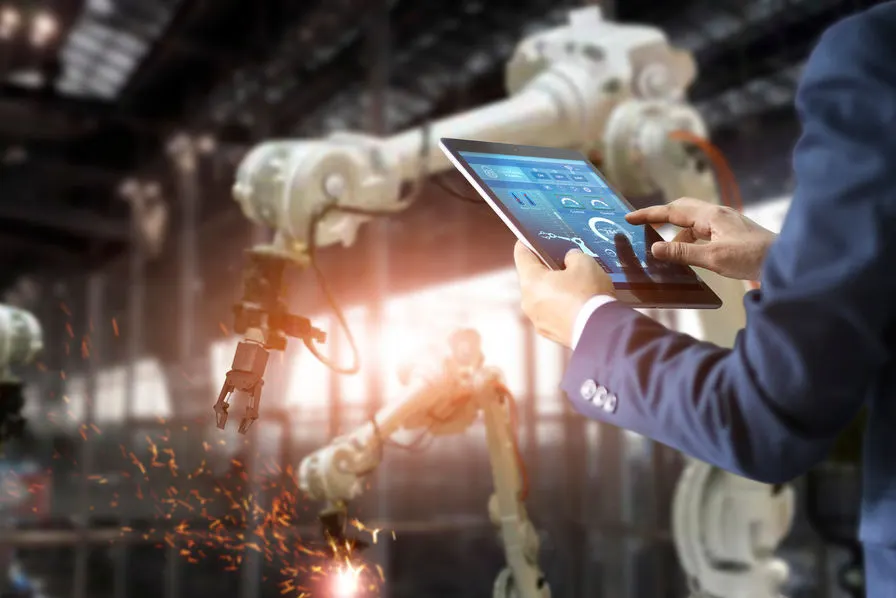 Tablette de pilotage devant des robots industriels